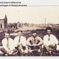 Vier jonge mannen op de grond met op de achtergrond enkele houten gebouwen en een koets in Chatham, Ontario.